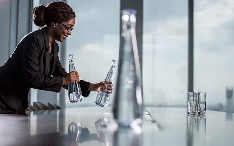 女士把玻璃水瓶放在办公室会议桌上