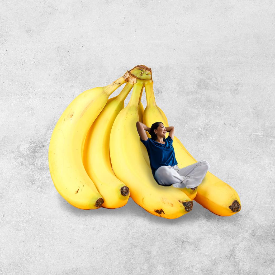 Woman lying back on an oversized bunch of yellow bananas